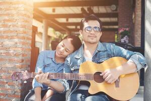 Hipster couple sitting relaxed with nice atmosphere with first date enjoys playing guitar as a great time together. photo