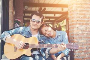 una pareja hipster sentada relajada con un ambiente agradable con la primera cita disfruta tocando la guitarra como un gran momento juntos. foto