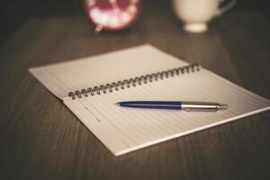 Vintage office desk table with notebooks, pen and a cup of coffee. With copy space. photo