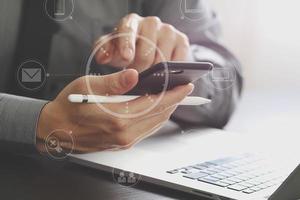 close up of businessman working with mobile phone and stylus pen and laptop computer on wooden desk in modern office photo