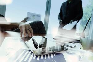 business documents on office table with smart phone and laptop and two colleagues discussing data in the background photo