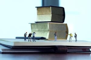 concepto de idea creativa: fotógrafo en miniatura con un libro dorado vintage en un cuaderno de papel abierto foto