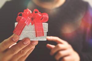 gift giving,man hand holding a gift box in a gesture of giving.blurred background,bokeh effect photo