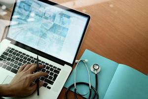 top view of Medicine doctor hand working with modern computer and smart phone on wooden desk as medical concept photo