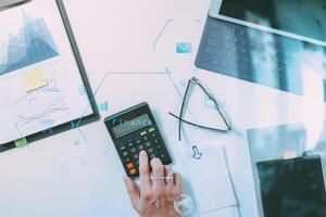 top view of businessman hand working with finances about cost and calculator and latop with mobile phone on withe desk in modern office photo