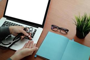 top view of Medicine doctor hand working with modern computer and blank screen laptop on wooden desk as medical concept photo