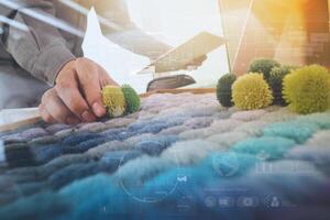 Interior designer hand chosing carpet sample with blank new modern computer laptop and pro digital tablet with material board on wooden desk as concept photo