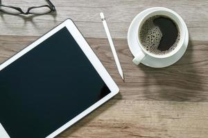 Coffee cup and Digital table dock smart keyboard,eyeglasses,stylus pen on wooden table,filter effect photo