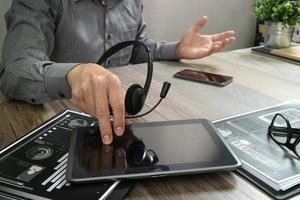 mano de hombre de negocios usando auriculares voip con tableta digital, documento, comunicación conceptual, soporte de TI, centro de llamadas y servicio de atención al cliente foto