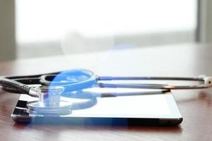 Studio macro of a stethoscope and digital tablet with shallow DOF evenly matched abstract on wood table background copy space photo