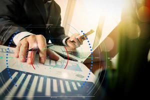 businessman hand working with new modern computer and business strategy documents with green plant foreground on wooden desk in office photo