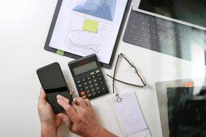 top view of businessman hand working with finances about cost and calculator and latop with mobile phone on withe desk in modern office photo