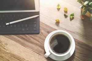 Coffee cup and Digital table dock smart keyboard,vase flower herbs,stylus pen on wooden table,filter effect photo