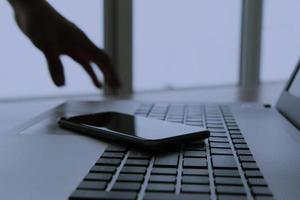 mano de hombre de negocios usando una computadora portátil y un teléfono móvil en un escritorio de madera como concepto nocturno foto