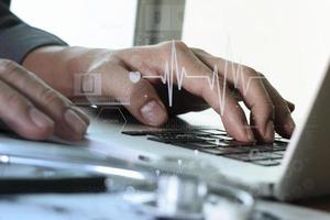 close up of Medicine doctor hand working with modern computer and medical diagram layers on wooden desk as medical concept photo