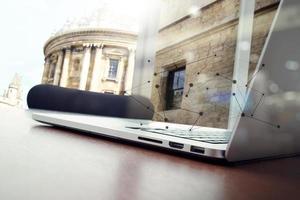 lugar de trabajo de oficina con computadora portátil y teléfono inteligente en una mesa de madera y fondo de edificio histórico foto