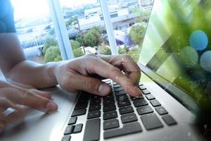 designer hand working with laptop and business digital layer diagram with green plant foreground photo