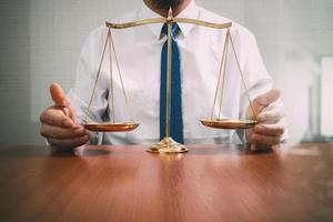 concepto de justicia y derecho.abogado masculino en la oficina con escala de latón sobre mesa de madera,vista reflejada foto