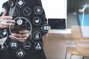 smart medical doctor working with smart phone and digital tablet and laptop computer on dark wooden desk in modern office with virtual icon diagram photo