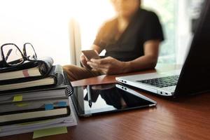 designer hand working with  digital tablet and laptop and notebook stack and eye glass on wooden desk in office photo