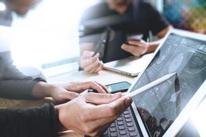 two colleague web designer discussing data and digital tablet docking keyboard and computer laptop with smart phone and design diagram on marble desk,sun light effect photo