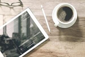 Coffee cup and Digital table dock smart keyboard,eyeglasses,stylus pen on wooden table,filter effect photo