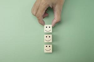 primer plano escogió a mano el cubo de símbolo de icono de cara de sonrisa de cara feliz sobre fondo verde foto