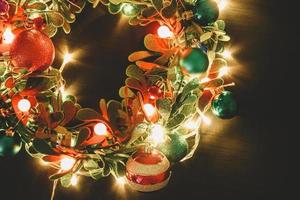 Greeting Season concept.Christmas wreath with decorative light on dark wood background photo