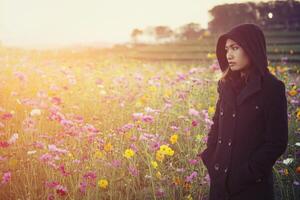 hermosas mujeres con abrigo negro, de pie en un campo de flores. foto