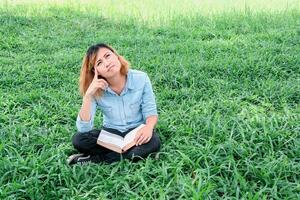 young hipster woman reading a book has an idea pointing with finger up. photo