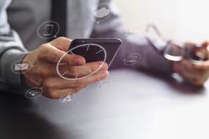 close up of businessman working with mobile phone and eyeglass on wooden desk in modern office photo