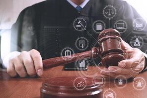 justice and law concept.Male judge in a courtroom striking the gavel,working with digital tablet computer docking keyboard on wood table,virtual interface graphic icons diagram photo