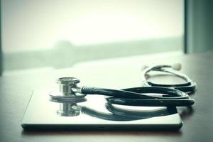 Studio macro of a stethoscope and digital tablet with shallow DOF evenly matched abstract on wood table background copy space photo