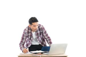 joven empresario mirando y escribiendo en su bloc de notas sentado en su lugar de trabajo aislado sobre fondo blanco. foto