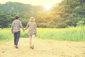 Young hipster couple taking a walk on beautiful flower field. photo