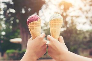 Woman's hands holding melting ice cream waffle cone in hands on summer light nature background photo