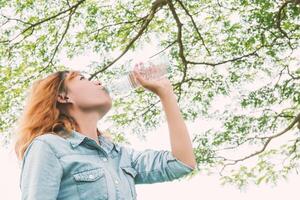 mujer vida joven mujer hermosa agua potable en el parque verde. foto