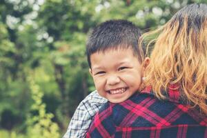 pequeño y lindo niño asiático abrazo con su madre y sonriendo a la cámara tiempo feliz. foto