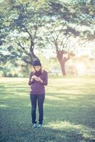 Beautiful Woman standing in park writing text on smartphone photo