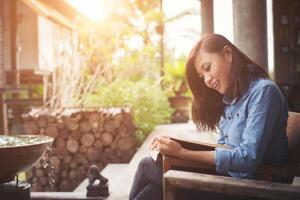 mujer joven leyendo un libro sentado en la silla. vacaciones relajantes disfrutar de la lectura. foto