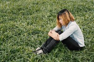 young hipster woman, sad, long-haired  sitting hugging legs. photo