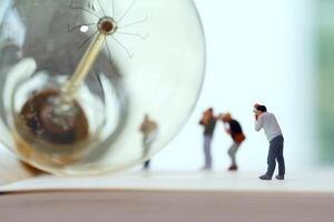 Creative idea concept - miniature photographer with vintage light bulb on open paper notebook photo