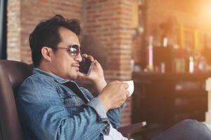 joven con smartphone sonriendo relajándose en el café. foto