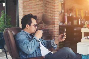 joven con smartphone sonriendo relajándose en el café. foto