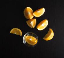 Sliced oranges with glass on black background photo