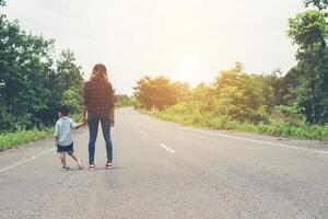 Mother holding a hand of his son in summer day walking on the street. photo