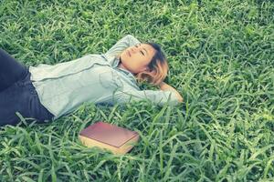 Young hipster woman lying down on grass when she tired after read book. photo