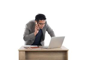 Businessman working on laptop and calling on phone, white background. photo