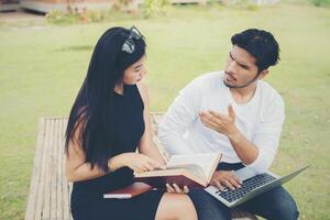 Young education couple sitting on the bench in the outdoors and good weather. And they're happy, Lifestyle concept. photo