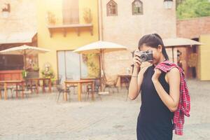 mujer hermosa joven con cámara retro, chica asiática de estilo retro vintage de vacaciones sonriendo feliz. foto